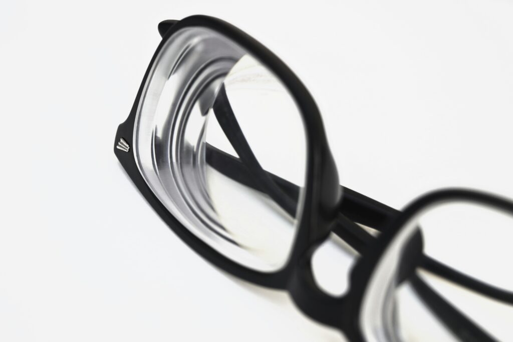 Modern black frame eyeglasses close-up on white surface, showcasing stylish eyewear design.
